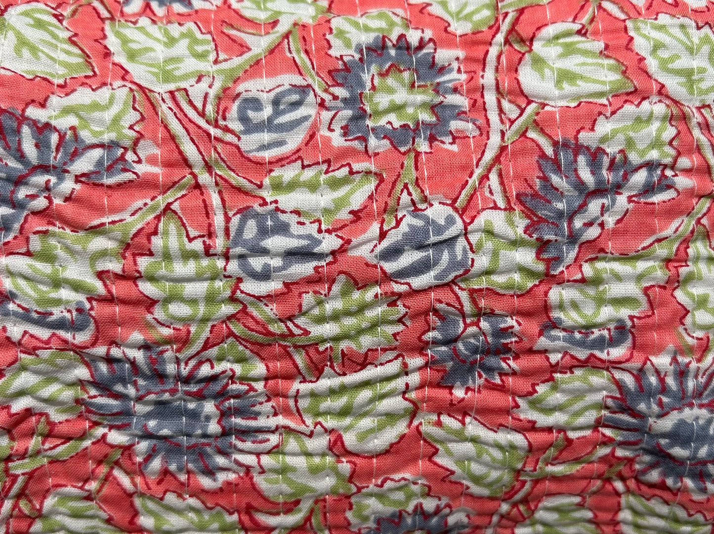 A quilted cotton block printed wash bag with a floral pattern, featuring a zipper with a tassel, and finished with a waterproof lining.
